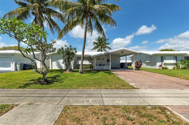 view of front of house featuring decorative driveway, a front yard, and an attached carport