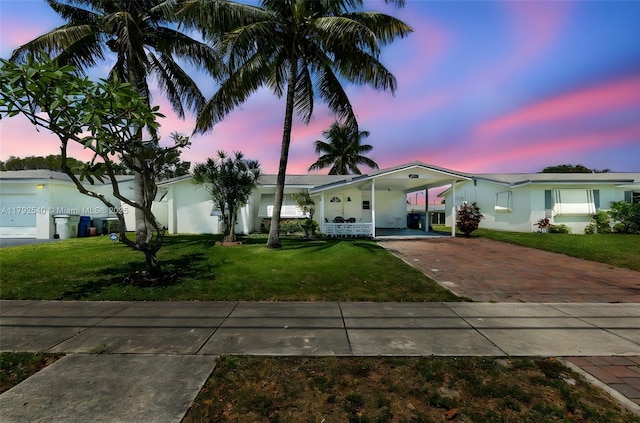 single story home featuring a lawn, stucco siding, an attached carport, and concrete driveway
