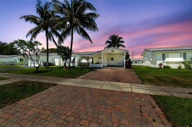 view of front facade featuring a lawn, decorative driveway, and stucco siding