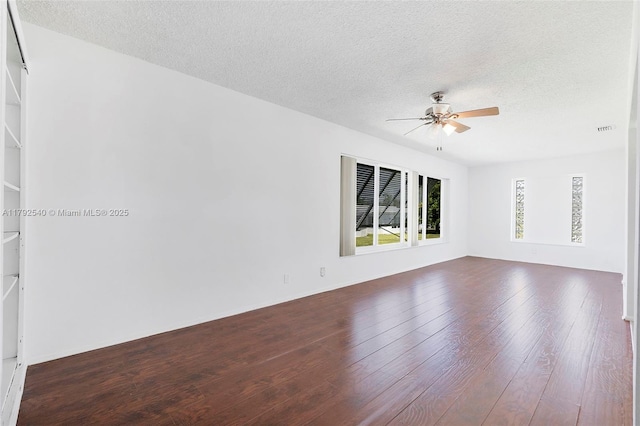 unfurnished room featuring ceiling fan, dark wood-style flooring, a textured ceiling, and visible vents