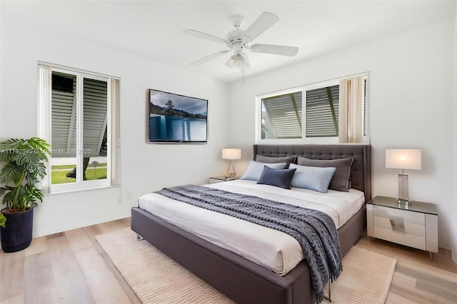 bedroom with ceiling fan, wood finished floors, and multiple windows