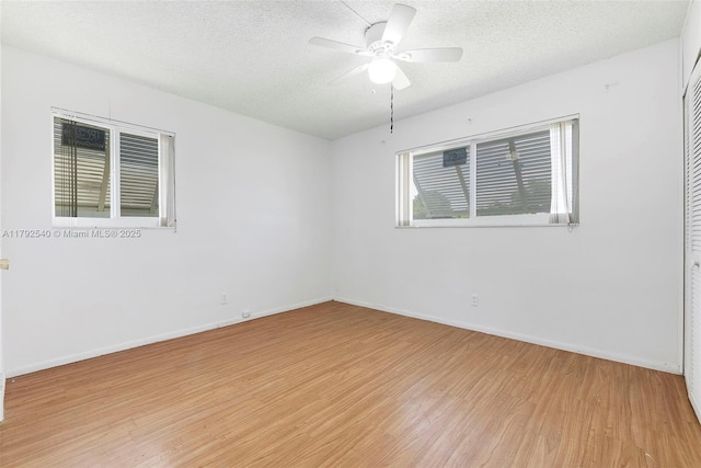 empty room with baseboards, a textured ceiling, light wood-style flooring, and ceiling fan