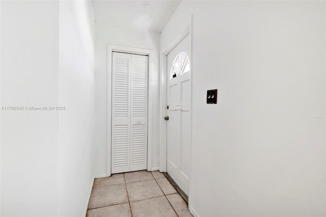 doorway featuring light tile patterned flooring and baseboards