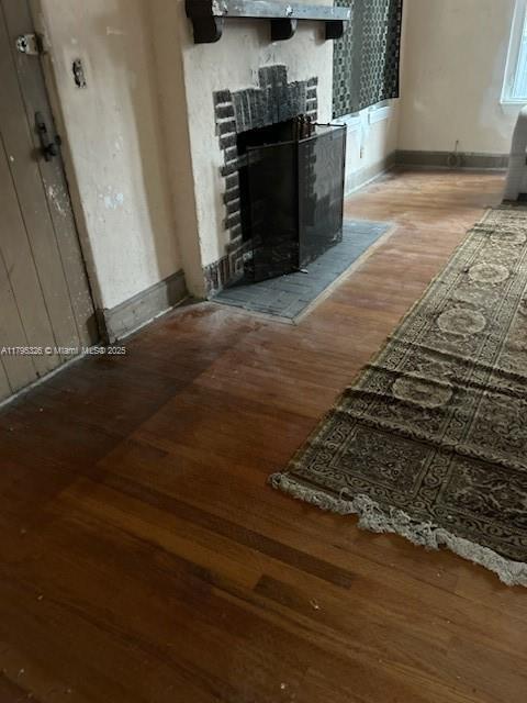 interior details with baseboards, wood finished floors, and a tile fireplace