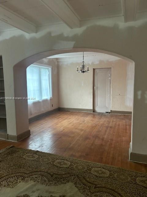 interior space with arched walkways, beam ceiling, and wood finished floors