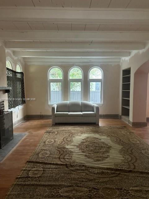 interior space with arched walkways, beamed ceiling, plenty of natural light, and baseboards
