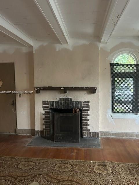 details with beam ceiling, wood finished floors, and a fireplace