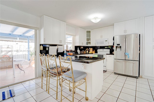 767 NW 122nd Pl, Miami, FL 33182 - kitchen featuring light tile patterned floors, white cabinets, white appliances, and a kitchen bar