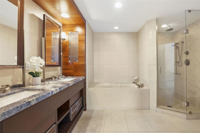 full bath with a sink, tile patterned flooring, tile walls, a garden tub, and a stall shower