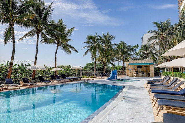 community pool featuring a hot tub, a patio area, and exterior bar