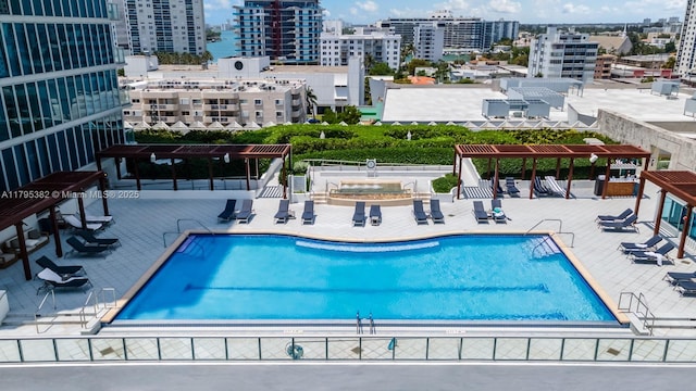 pool with a pergola, a city view, and a patio