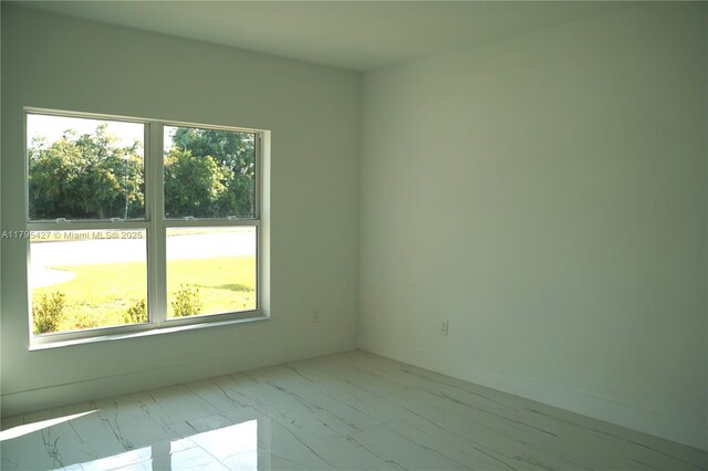 spare room featuring marble finish floor and a healthy amount of sunlight