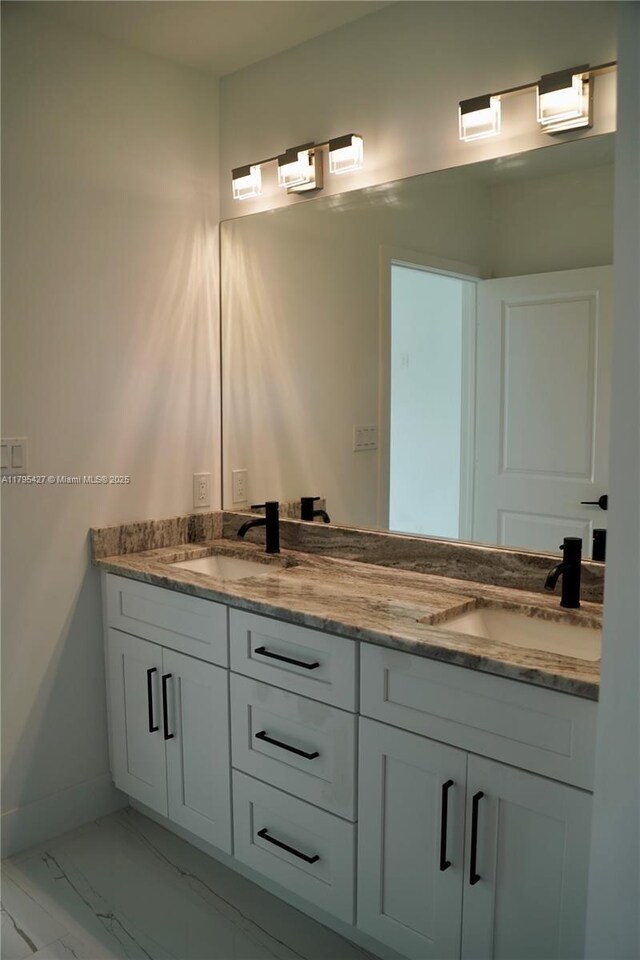 bathroom featuring a sink, baseboards, double vanity, and marble finish floor