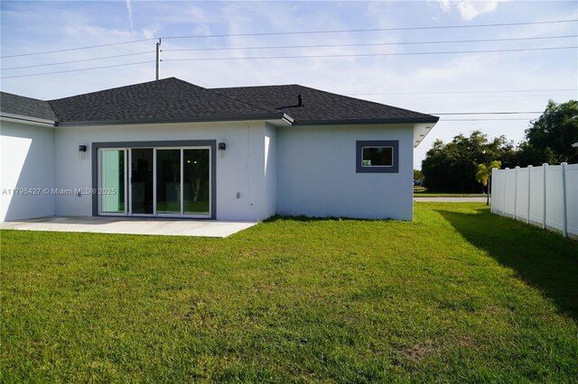 rear view of house with a yard, a patio area, and stucco siding