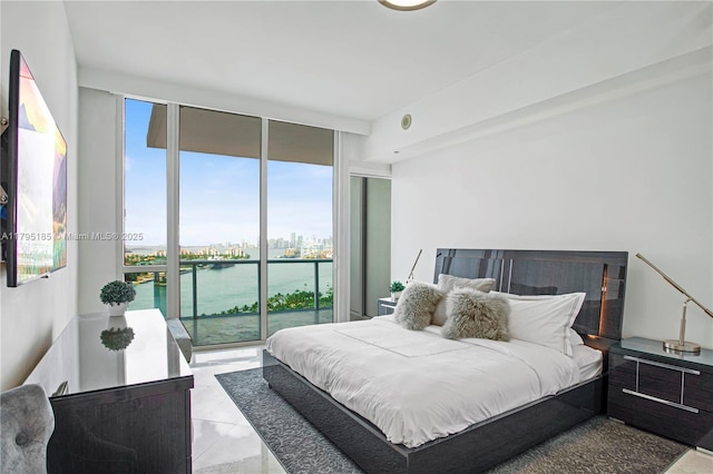 bedroom featuring a water view, access to outside, and floor to ceiling windows