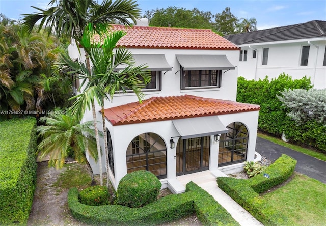 rear view of property with a tile roof and stucco siding