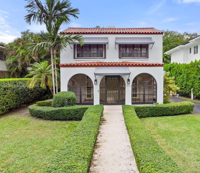 view of front of home featuring a front lawn, stucco siding, a balcony, and a tile roof