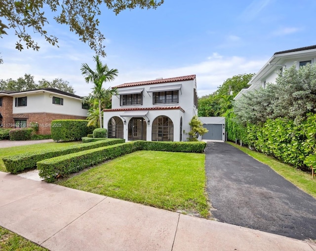 mediterranean / spanish-style home featuring a tiled roof, covered porch, stucco siding, and a front lawn