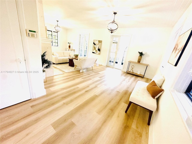 living area featuring an inviting chandelier, crown molding, and wood finished floors
