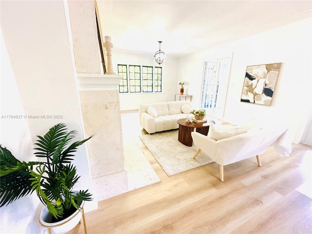 living area featuring crown molding, wood finished floors, and a notable chandelier