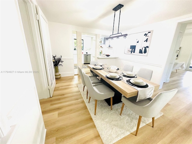 dining space featuring baseboards and light wood-type flooring