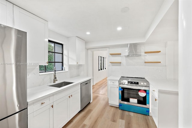 kitchen featuring open shelves, light wood-type flooring, wall chimney exhaust hood, a sink, and appliances with stainless steel finishes