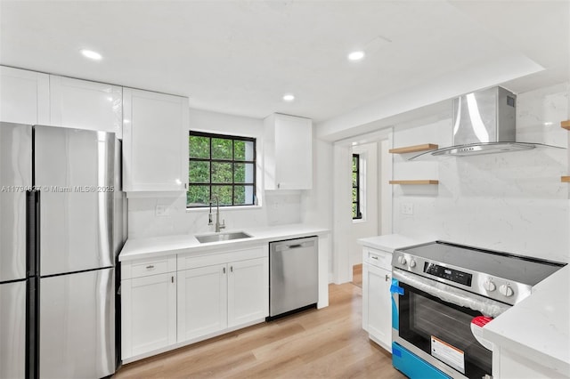 kitchen featuring open shelves, appliances with stainless steel finishes, a sink, wall chimney exhaust hood, and white cabinetry