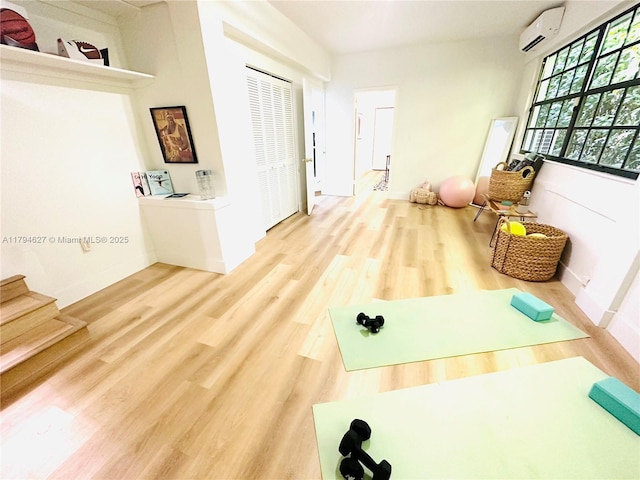 exercise area with baseboards, a wall mounted air conditioner, and wood finished floors