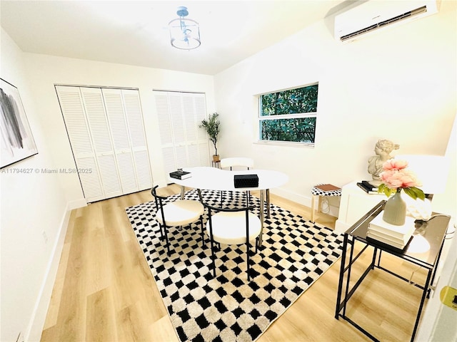 home office with light wood-style floors, baseboards, and a wall unit AC