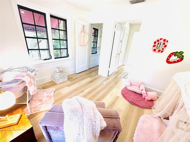 living area with baseboards, wood finished floors, and visible vents