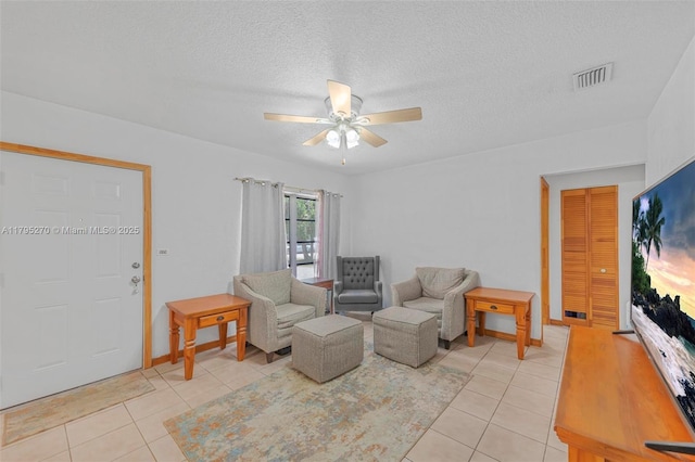 living room featuring a ceiling fan, a textured ceiling, visible vents, and light tile patterned floors