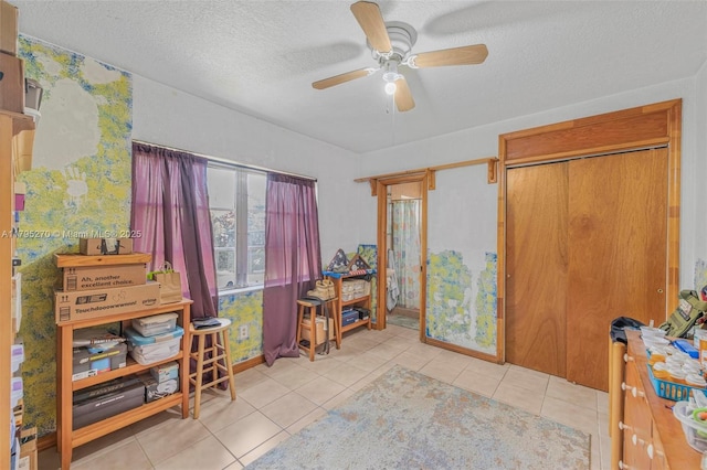 interior space with a textured ceiling, tile patterned floors, and ceiling fan