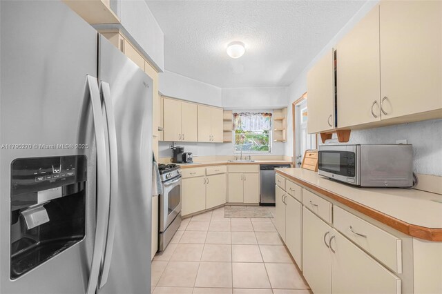 9240 Nautilus Dr, Cutler Bay, FL 33189 - kitchen with open shelves, light countertops, a textured ceiling, cream cabinetry, and stainless steel appliances