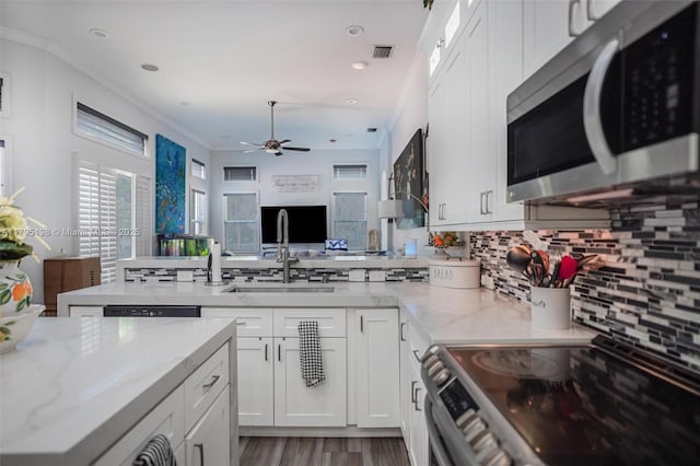 12307 NW 49th St, Coral Springs, FL 33076 - kitchen featuring stainless steel appliances, a sink, a peninsula, decorative backsplash, and white cabinetry