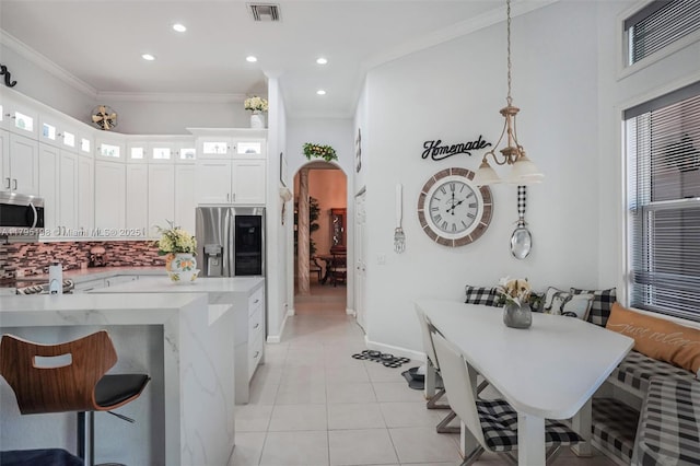 12307 NW 49th St, Coral Springs, FL 33076 - kitchen featuring appliances with stainless steel finishes, arched walkways, decorative backsplash, light tile patterned floors, and glass insert cabinets