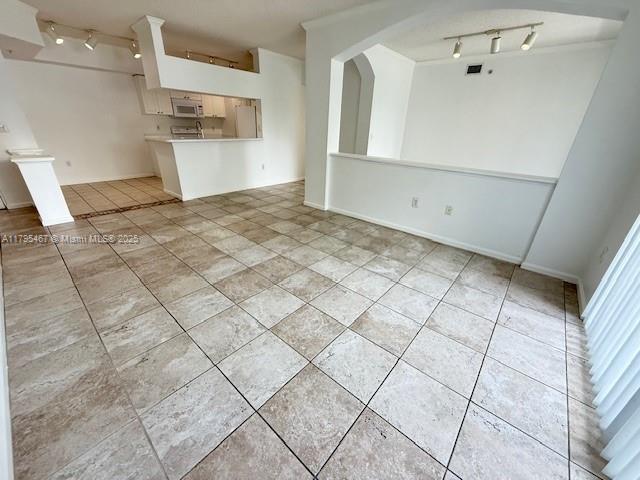 unfurnished living room with track lighting and light tile patterned flooring