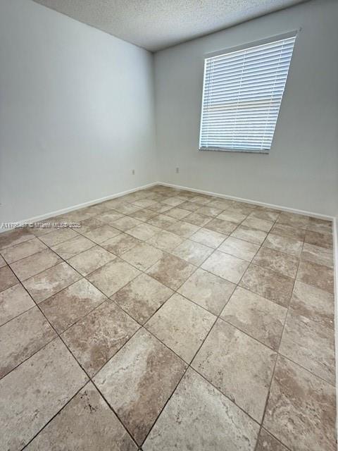 empty room featuring baseboards and a textured ceiling
