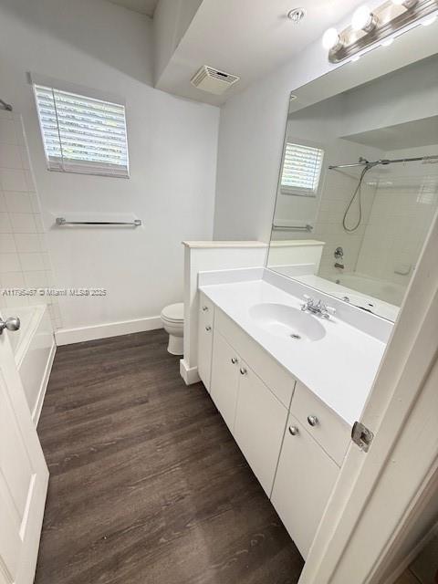 full bath featuring bathtub / shower combination, toilet, baseboards, wood finished floors, and visible vents