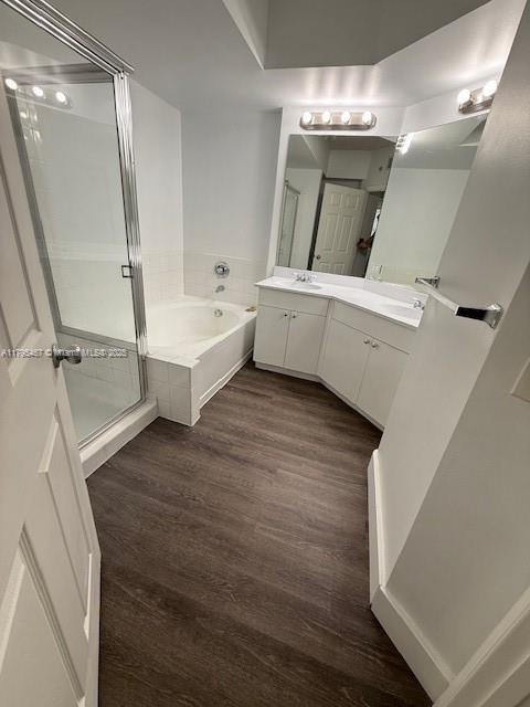 bathroom with vanity, a stall shower, a bath, and wood finished floors