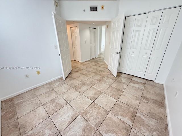 unfurnished bedroom with light tile patterned flooring, baseboards, visible vents, and a closet