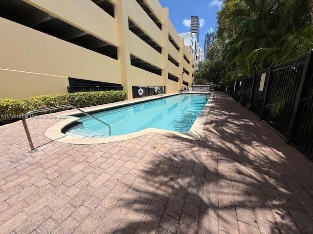 community pool with a patio area and fence
