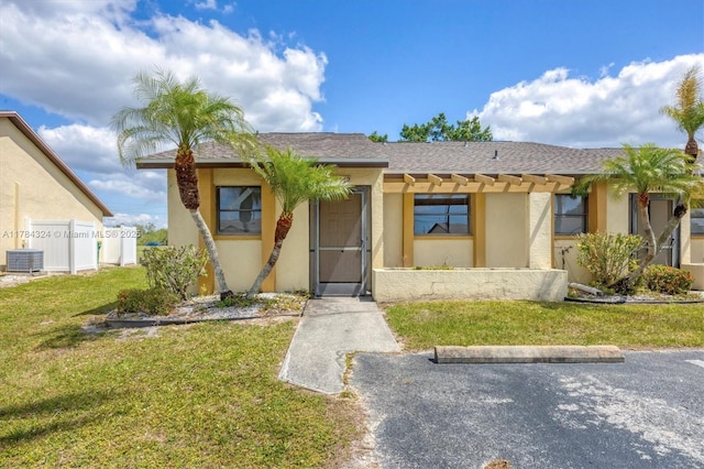 26136 Explorer St, Punta Gorda, FL 33983 - view of front of home with central air condition unit, fence, a front yard, and stucco siding