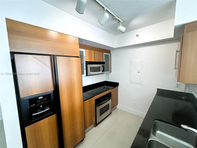 325 S Biscayne Blvd Unit 2917, Miami, FL 33131 - kitchen with stainless steel appliances, track lighting, light tile patterned flooring, a sink, and brown cabinets