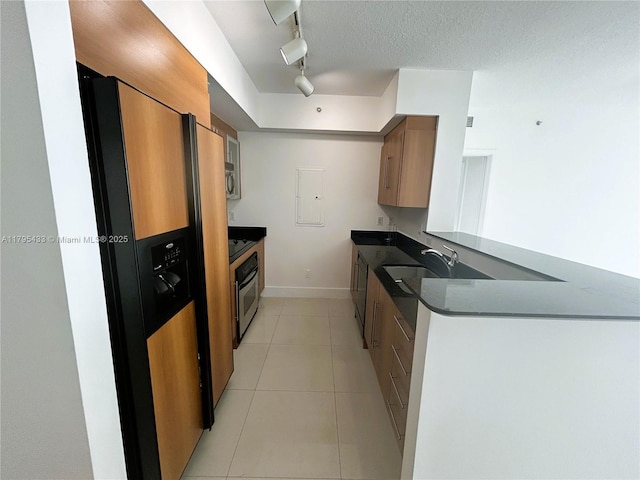 325 S Biscayne Blvd Unit 2917, Miami, FL 33131 - kitchen featuring stainless steel appliances, rail lighting, dark countertops, light tile patterned flooring, and brown cabinets