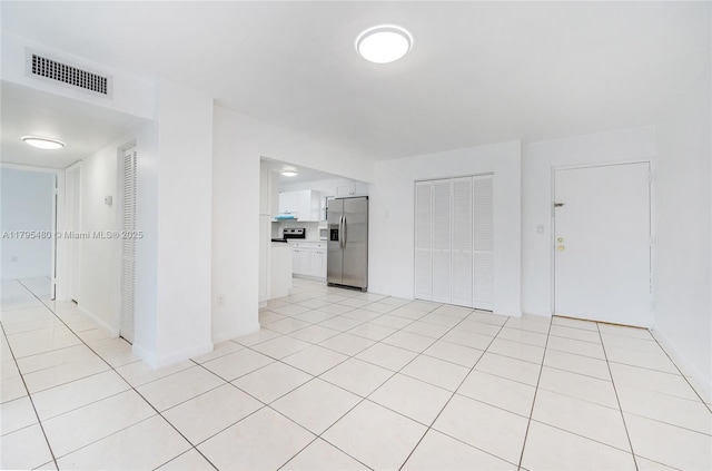 empty room featuring light tile patterned floors, baseboards, and visible vents