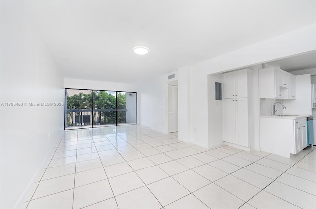 unfurnished living room featuring a sink, light tile patterned floors, baseboards, and visible vents
