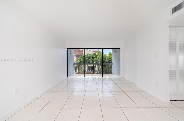 empty room with baseboards, visible vents, and light tile patterned floors