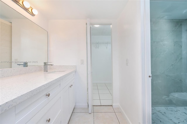 bathroom featuring vanity, baseboards, tile patterned floors, and toilet