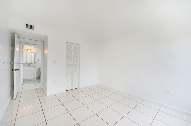 unfurnished bedroom with a closet, light tile patterned floors, and visible vents