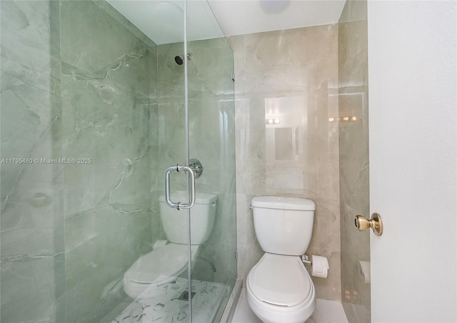 bathroom with tile walls, a shower stall, and toilet